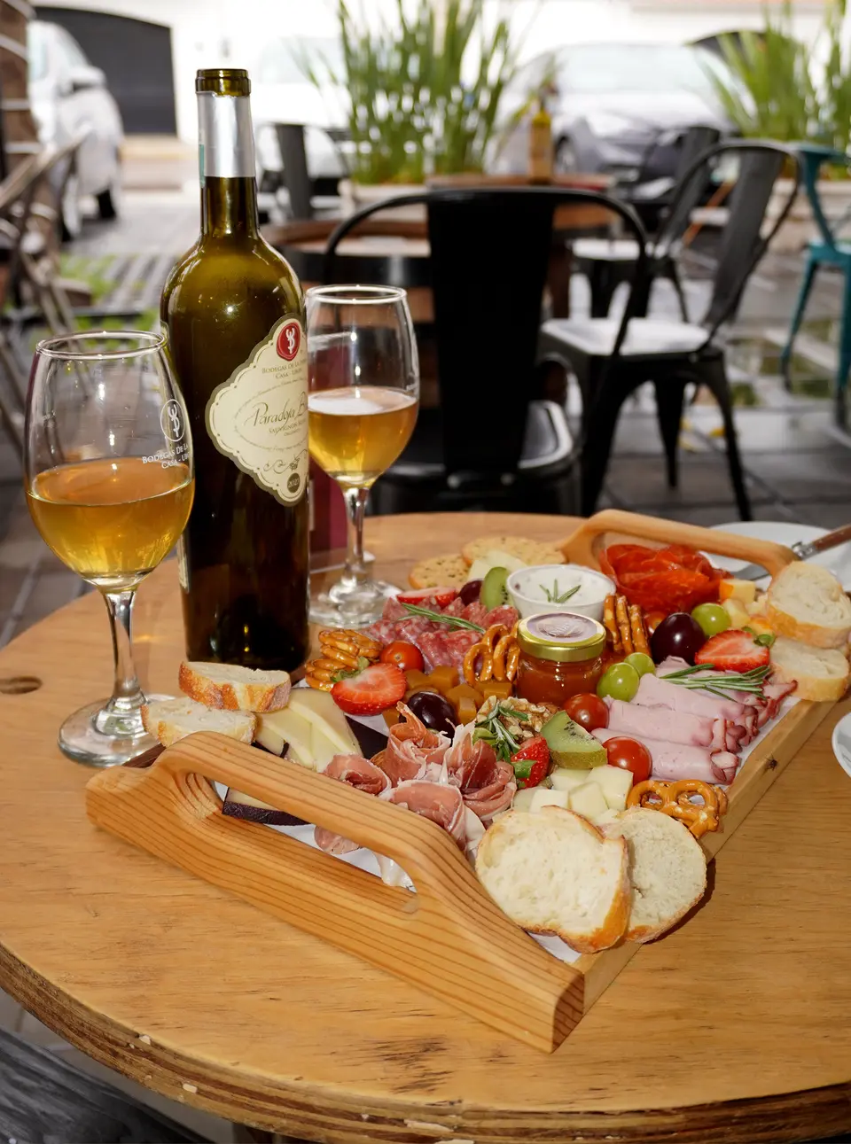 Tabla en la terraza con una botella de Paradoja Blanc y dos copas de vino blanco.
